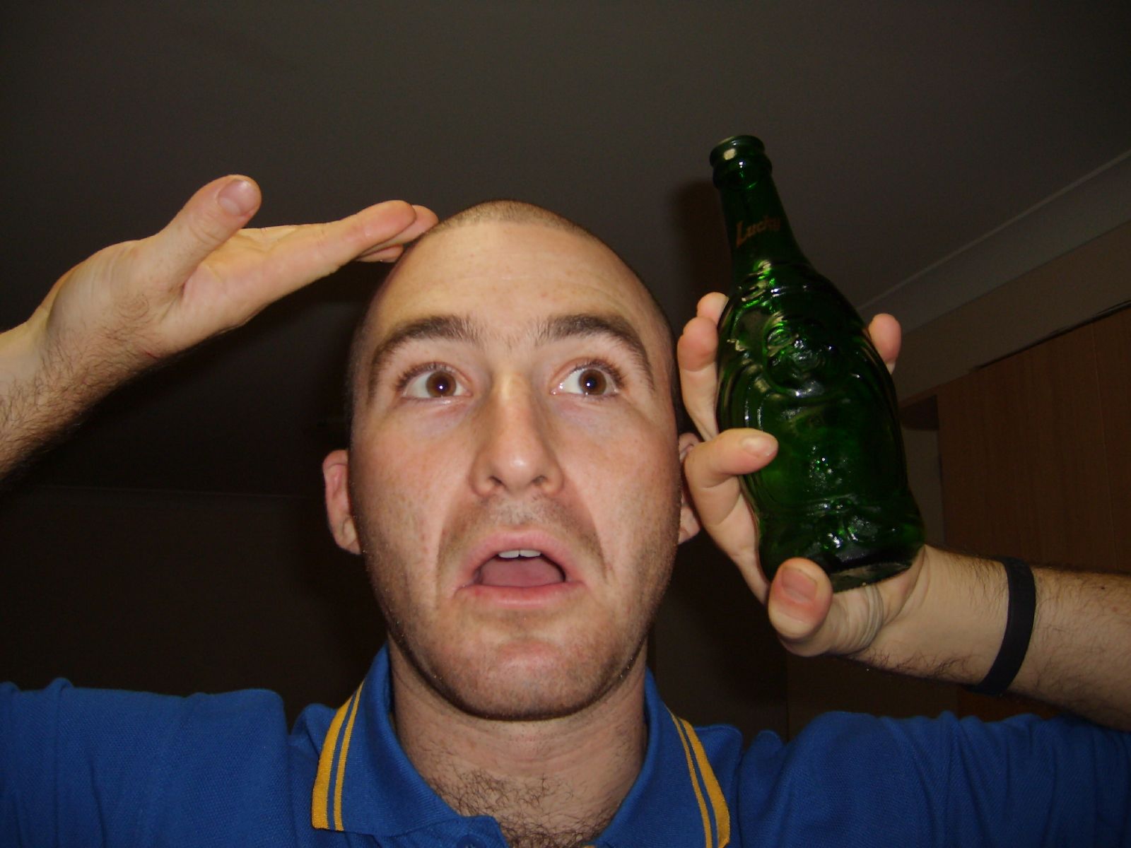 a man is looking at the camera holding a green bottle