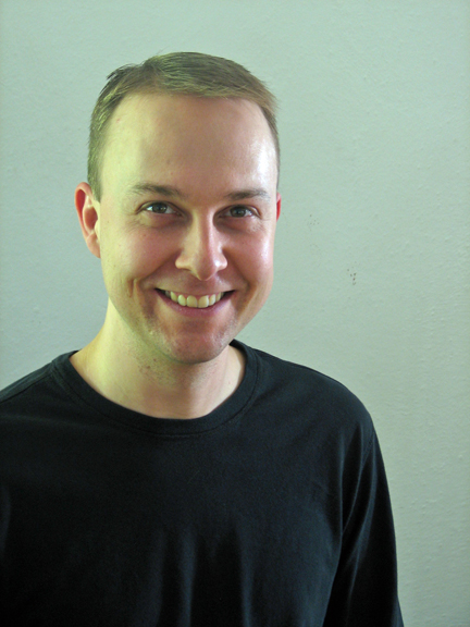 a man in black shirt smiling at the camera