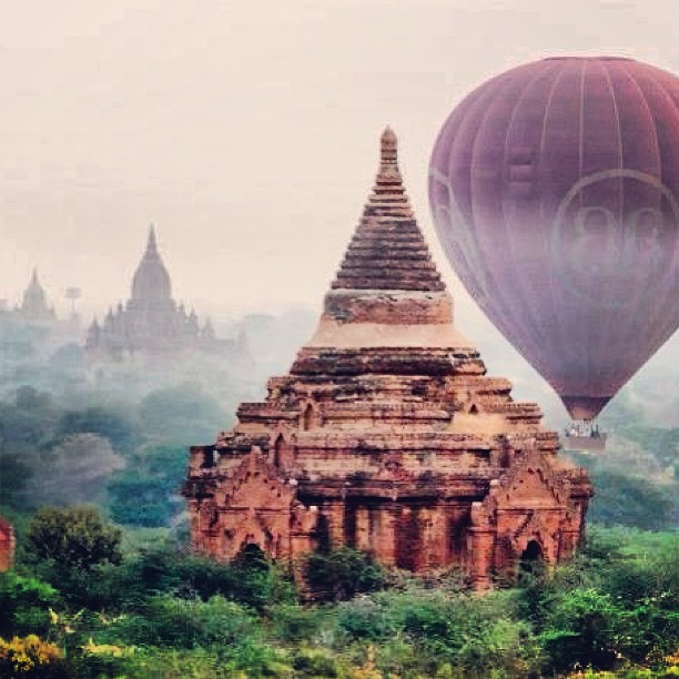 three  air balloons flying above an ancient temple
