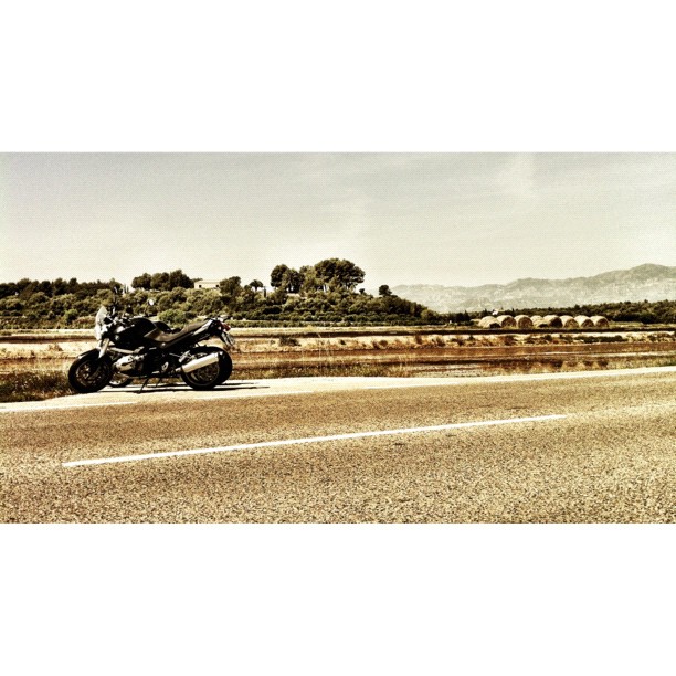 motorcycle leaning on the road in front of some hills