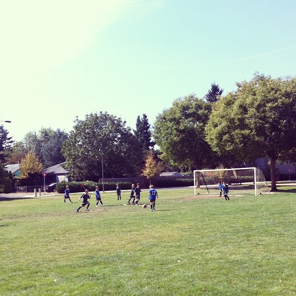 soccer teams running through a park playing soccer