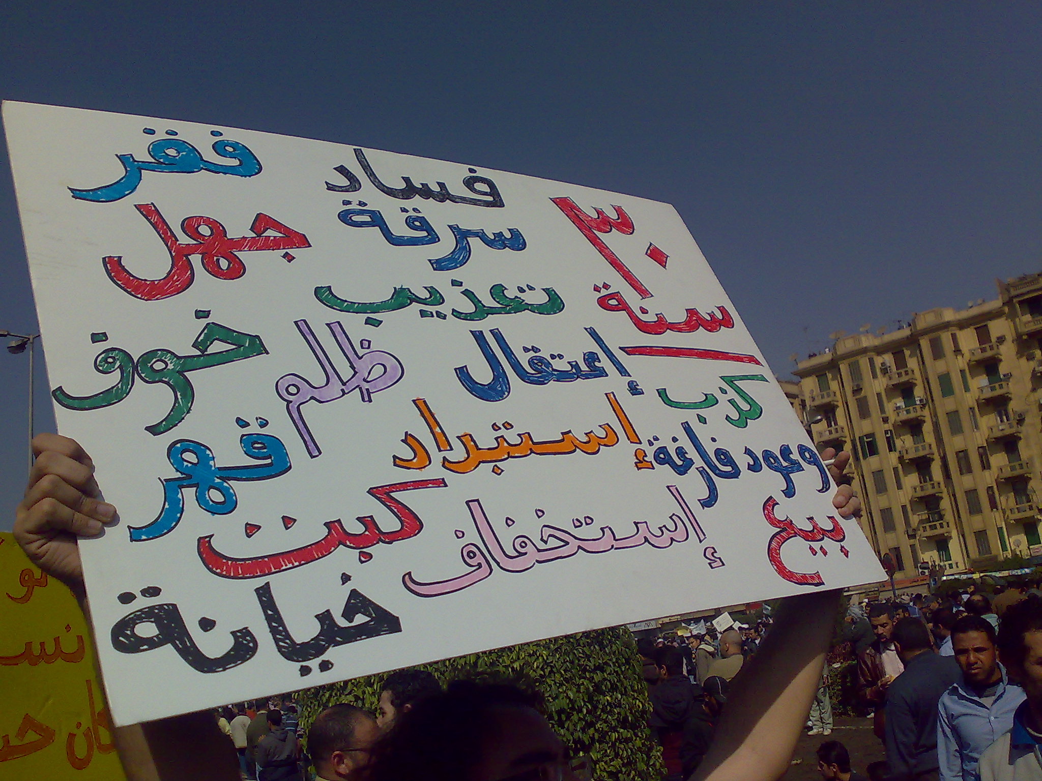 a person holding up a white sign in different languages