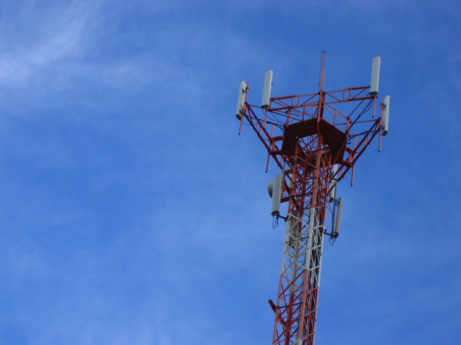 a cell tower stands tall against a bright blue sky
