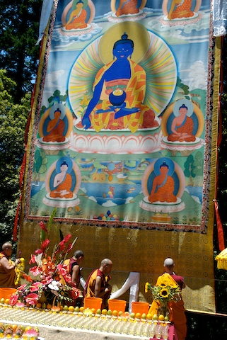 people are seated in a small temple under a huge banner