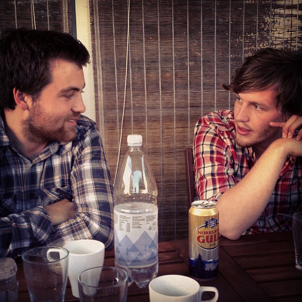 two men sit at a table and stare into each other's eyes