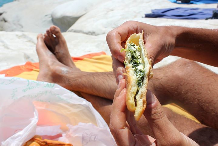 the sand is on the beach while someone is eating a sandwich