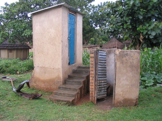 a small toilet with a door is out in the yard
