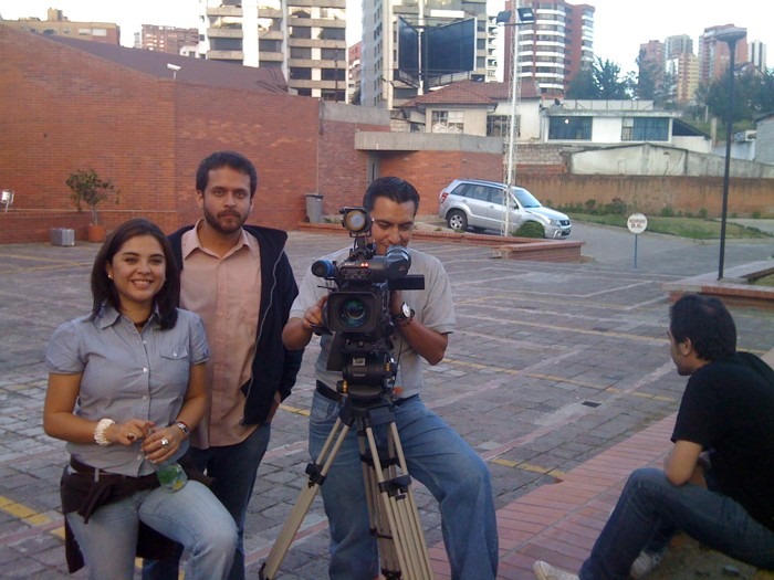 three people are standing and sitting in front of a camera