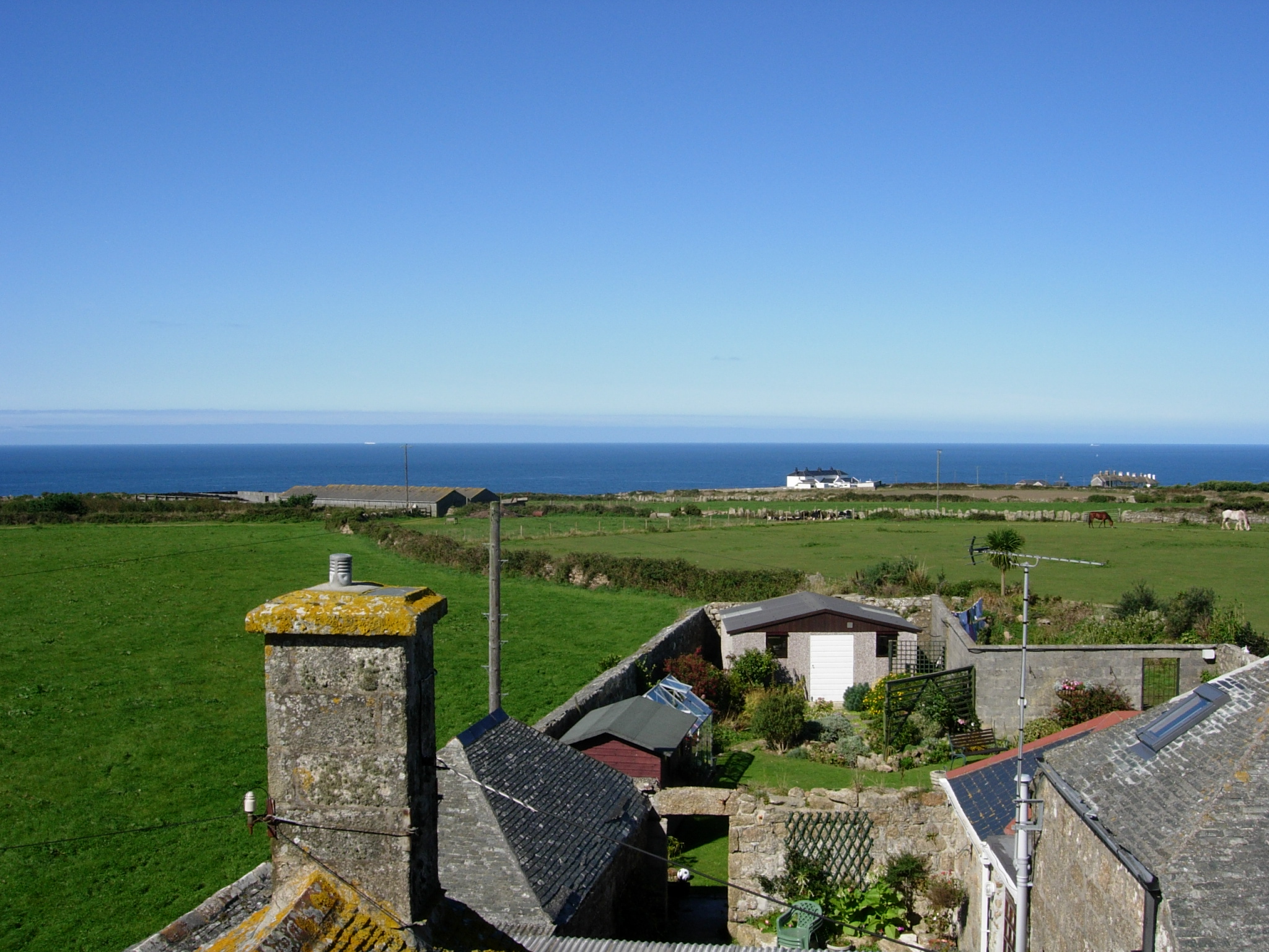 houses and fields with blue water in the background