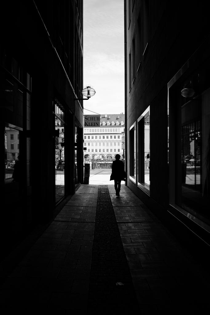 a black and white po of someone walking down the middle of an alley way