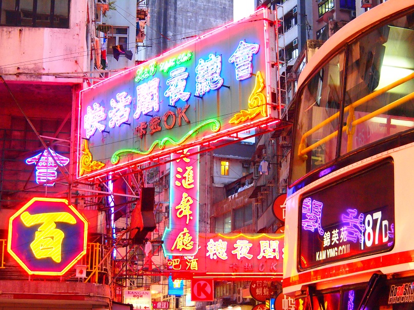 a couple of buses driving down a street in a busy asian city