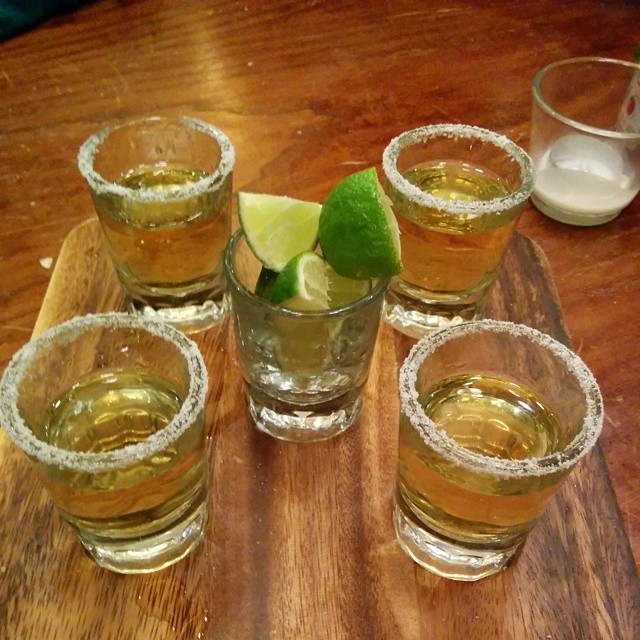 there are four glasses with liquid and a lime