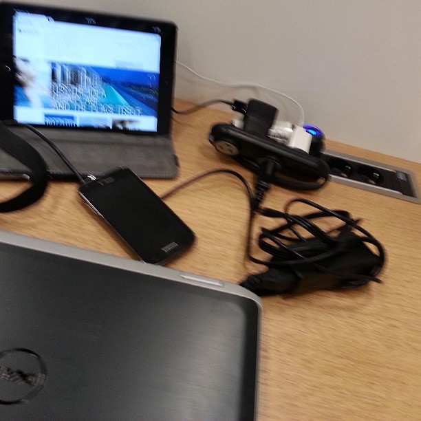 a table with a laptop and cords plugged into the back of it
