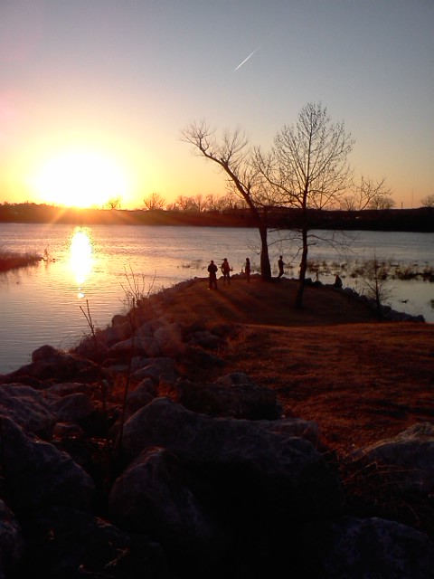 a lake at sunset with people standing on it
