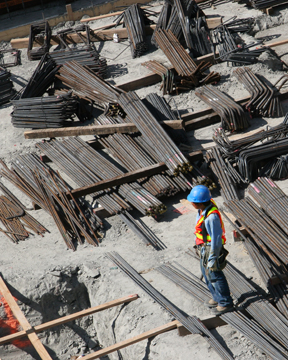 a man in blue and yellow jacket standing next to many wooden beams