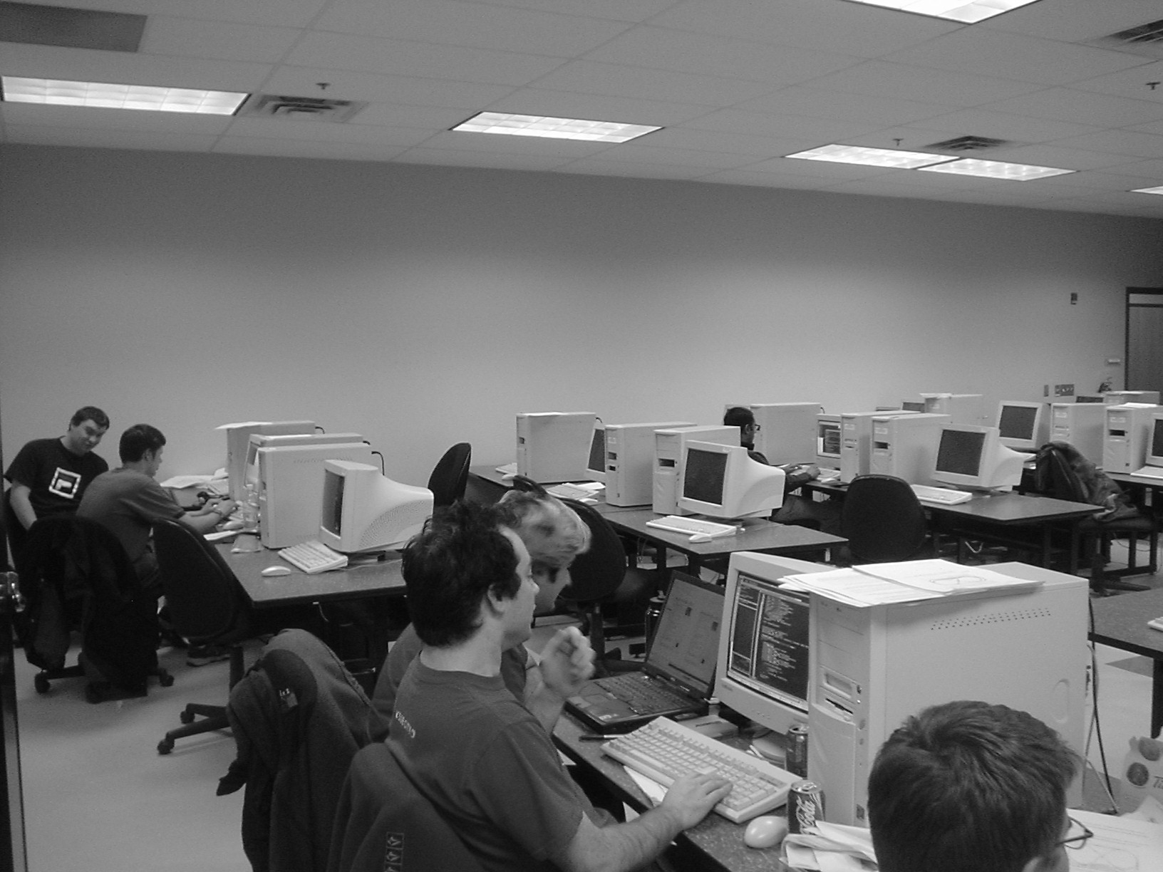 a computer lab with several people sitting at computers and typing on keyboards