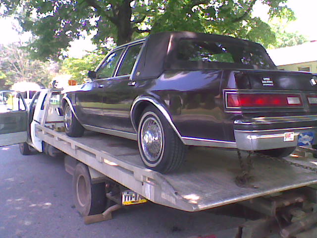 the back end of a black car on a flatbed truck