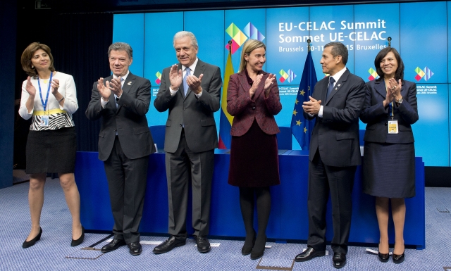 four people claps in front of a wall with flags
