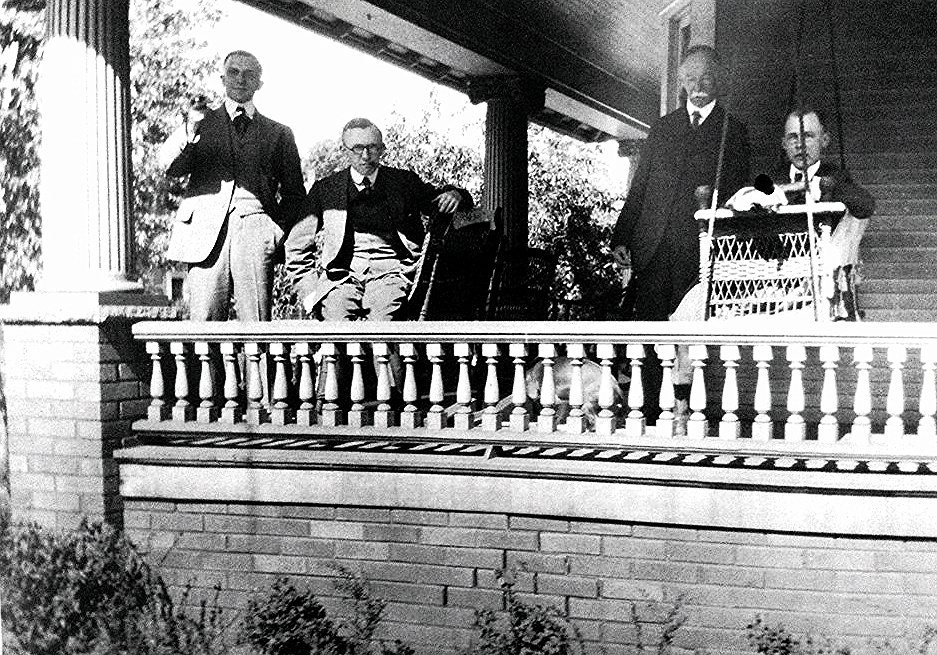 the four people are sitting outside of a house