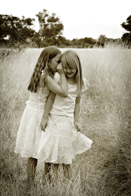 two little girls standing together in the tall grass