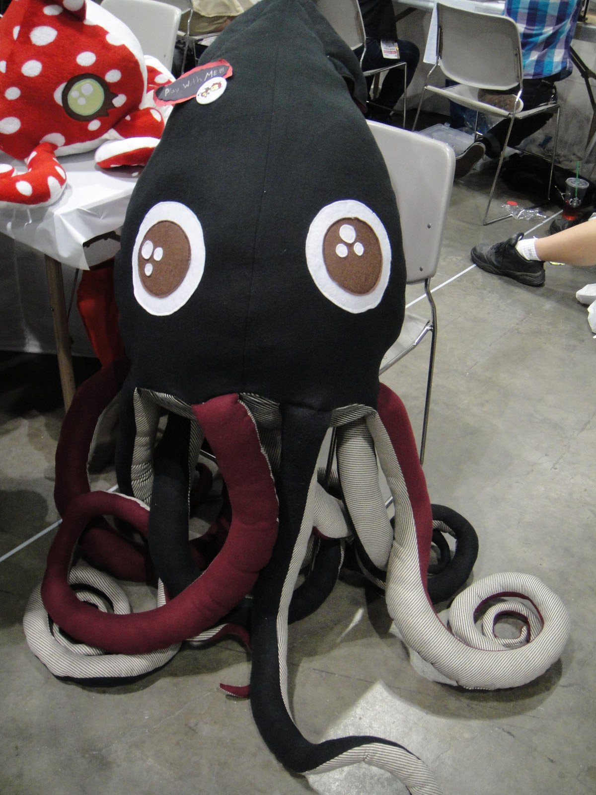 an octo stuffed in black sits on the ground