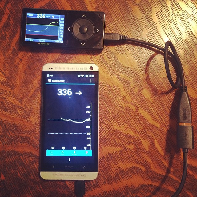 two smartphones with ear buds connected to a charger