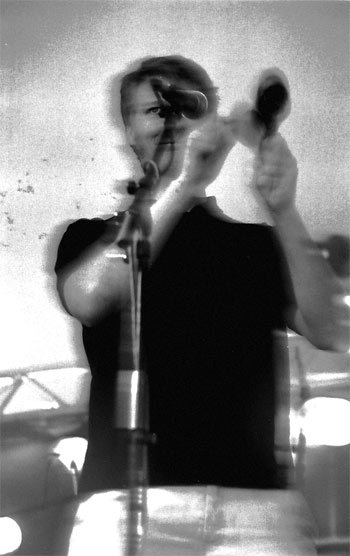 a woman standing in front of a microphone holding her hand up