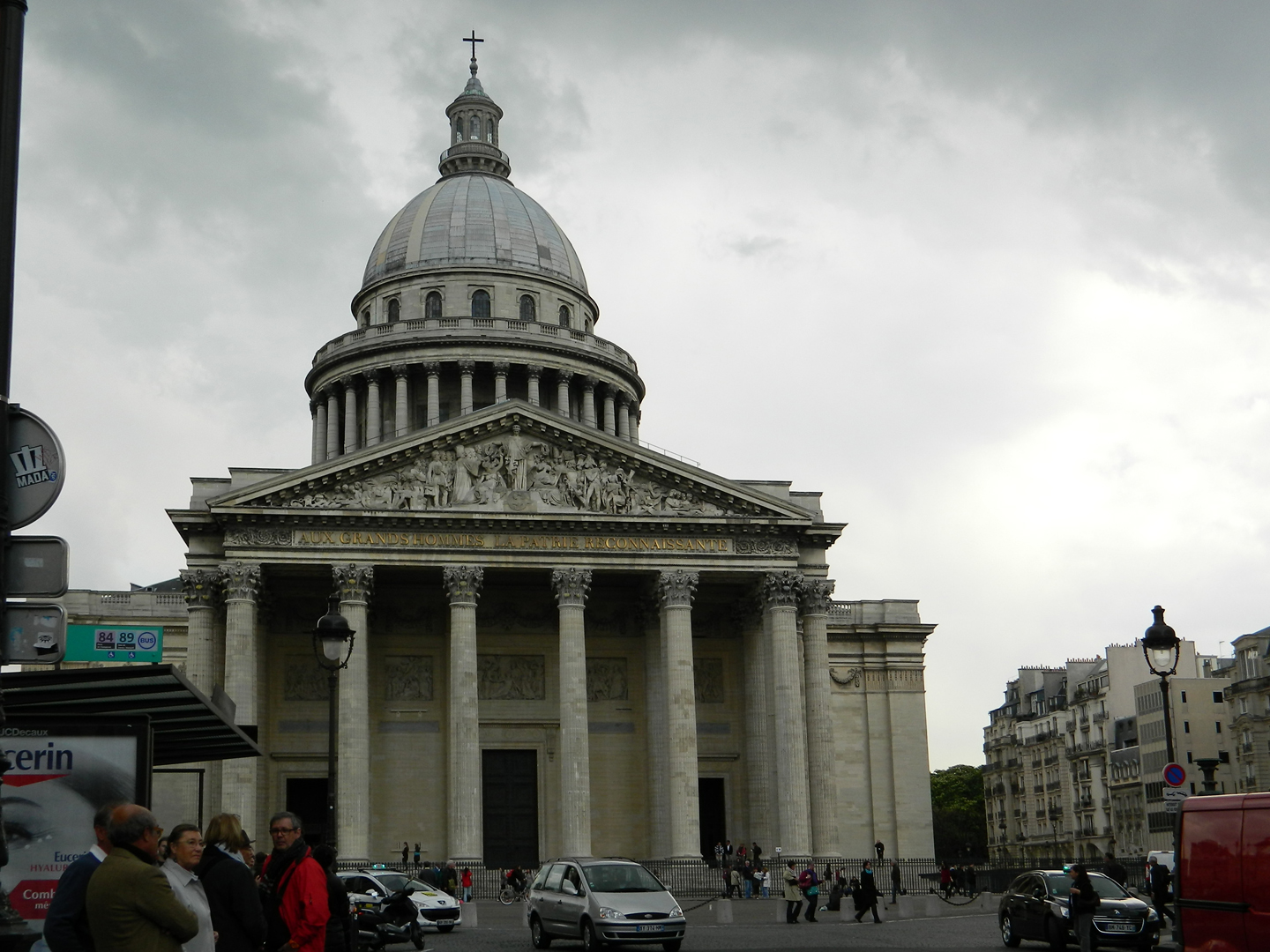 people gather in the streets as an architectural building stands