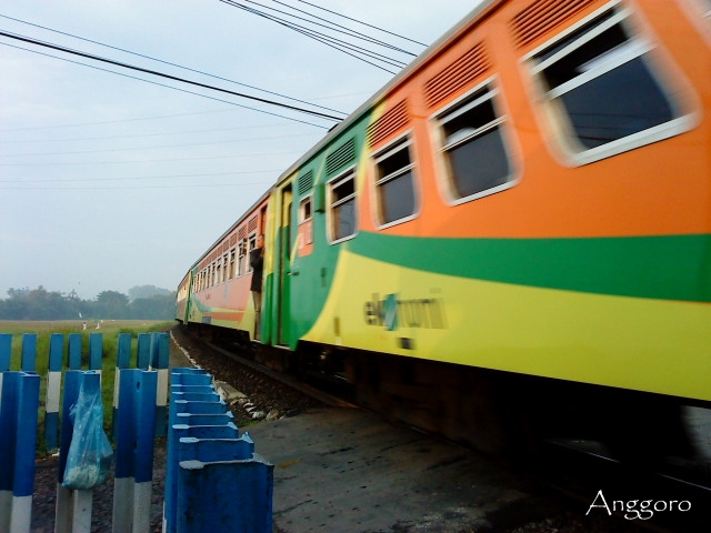 an orange green yellow and white train engine is passing by