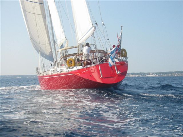 a red and white sail boat in the middle of the water