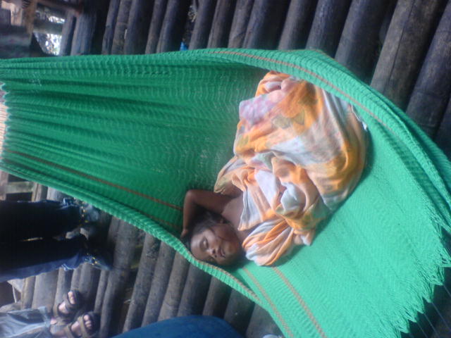 a child laying in a hammock next to some people