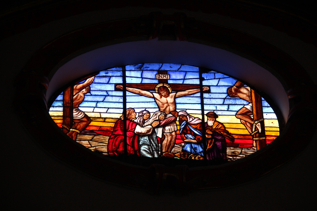 a stained glass window depicts the crucifix, jesus, mary and joseph