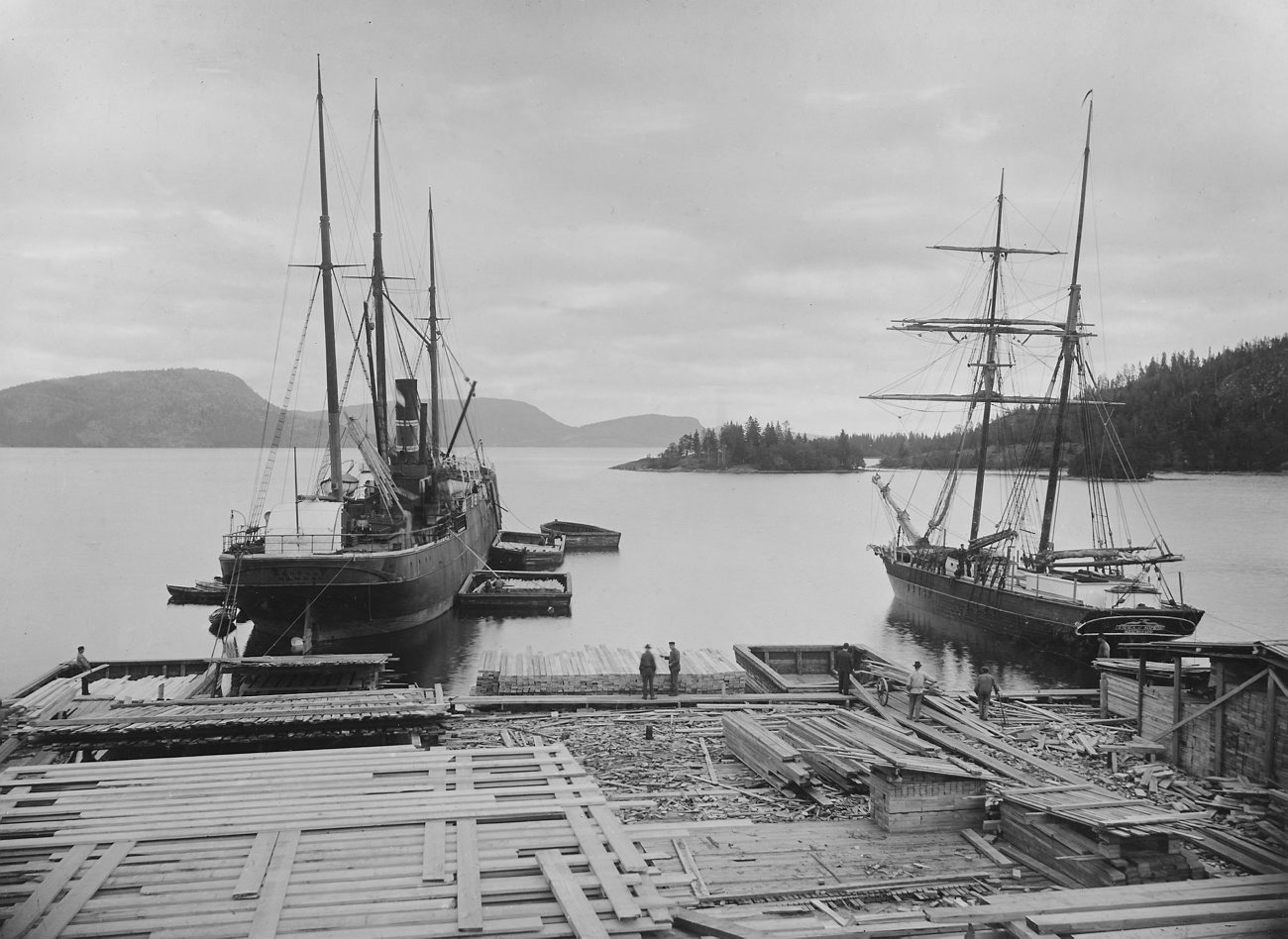 black and white pograph of two boats docked at a pier
