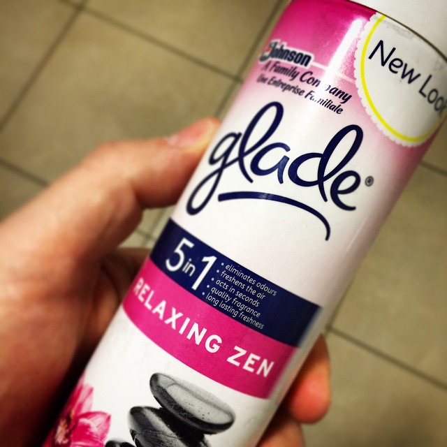 a hand holding a pink and white tube of deodorant