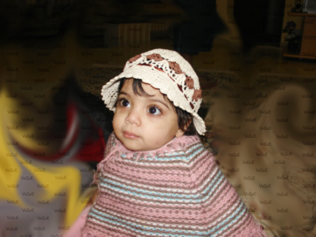 a little girl with a white crochet hat and a sweater