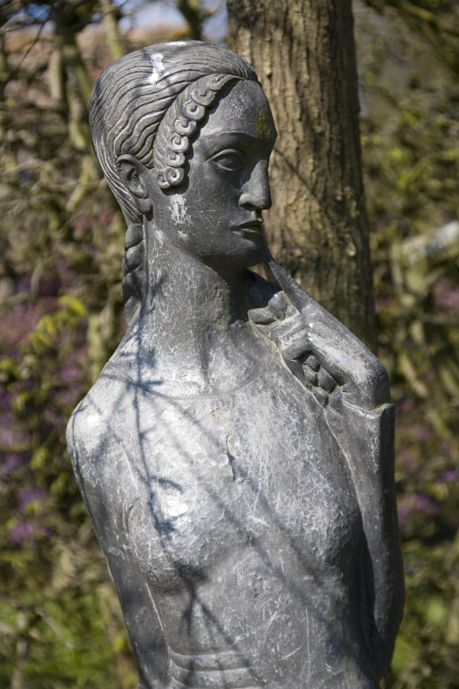 statue of an ancient woman near a tree