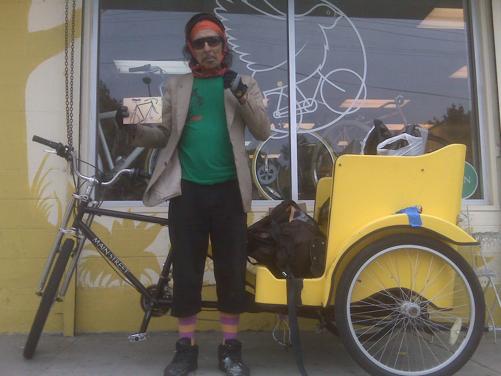 a man standing next to a yellow bicycle with the front tire up