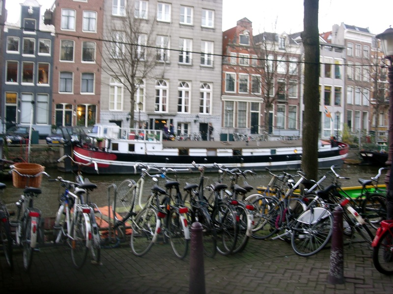 bicycles and boats lined up along a brick sidewalk