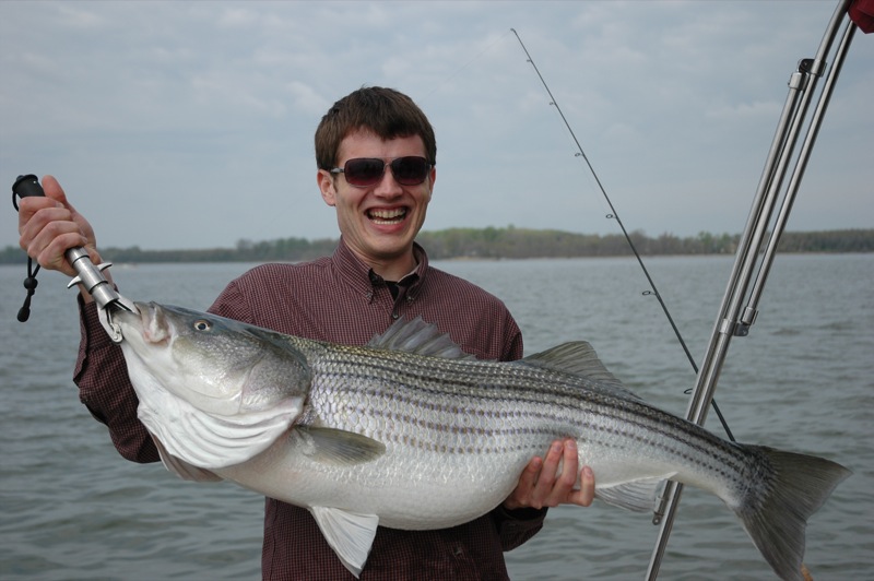a man holding up a fish and smiling