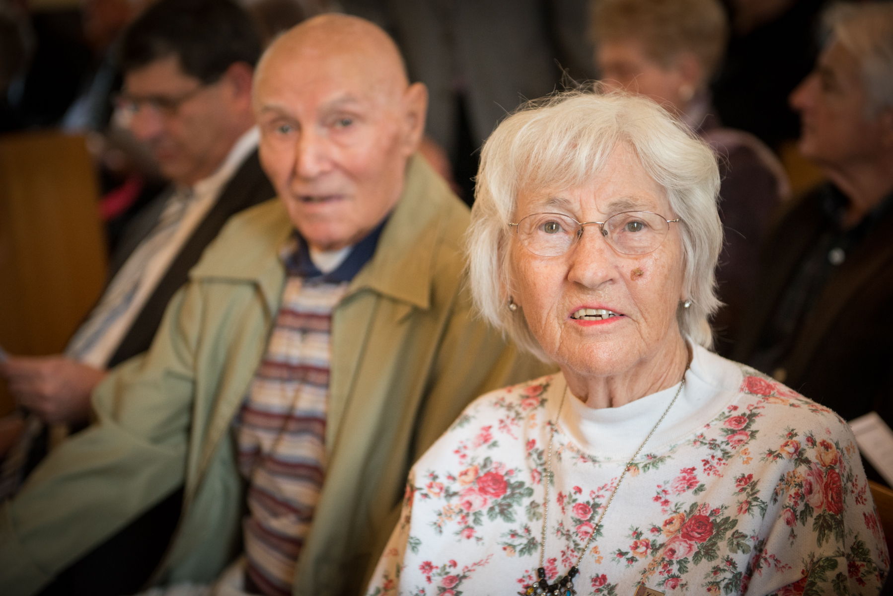 an elderly woman with a white coat and man next to her