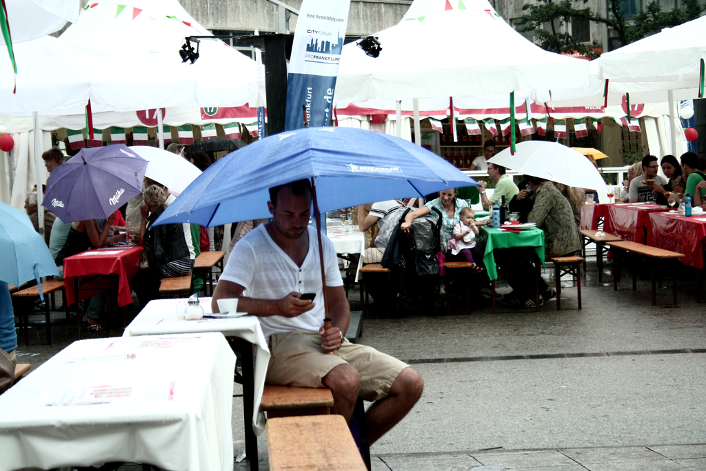 a man sitting under an umbrella on a bench