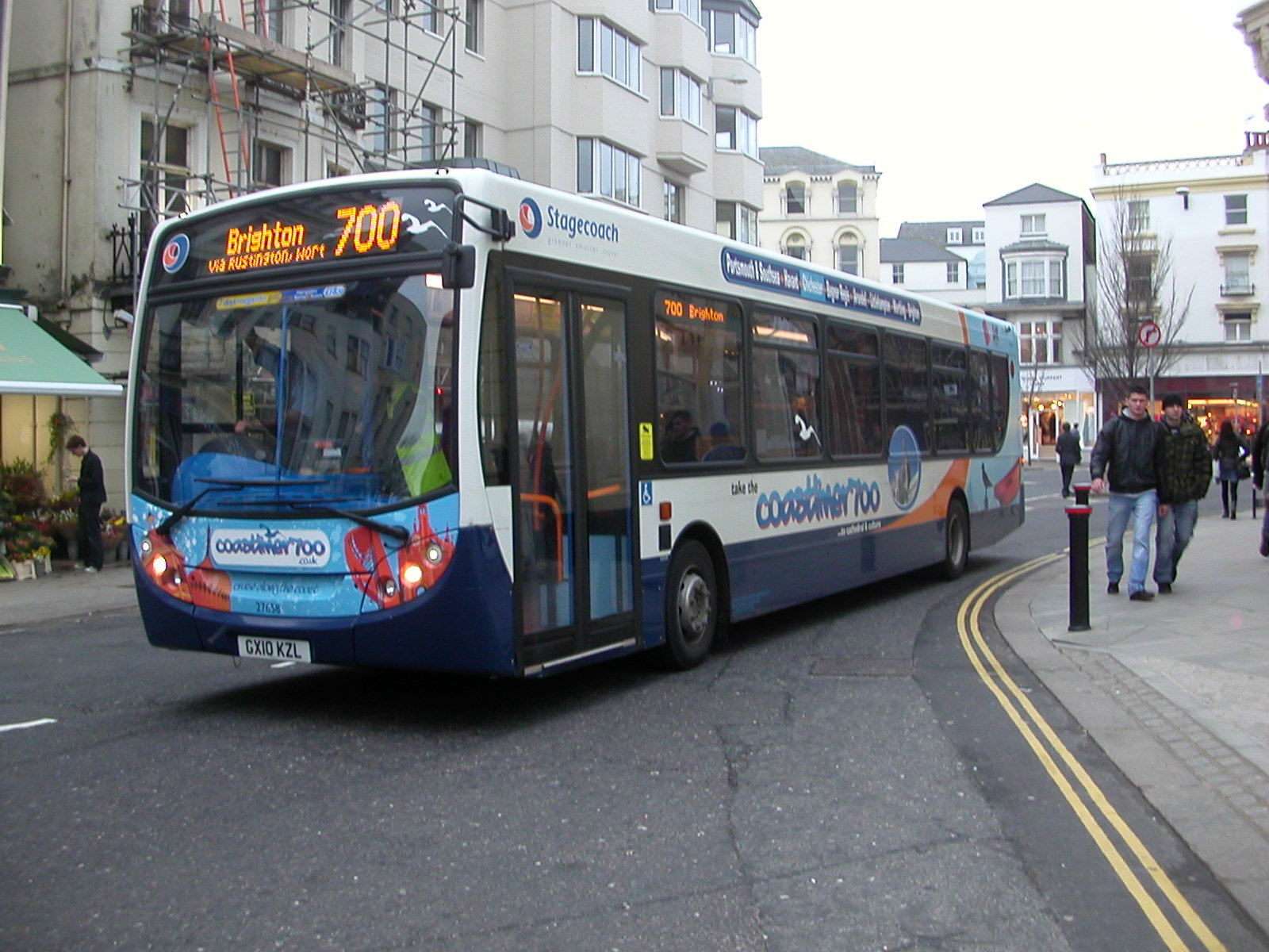 a blue and white city bus on a busy city street