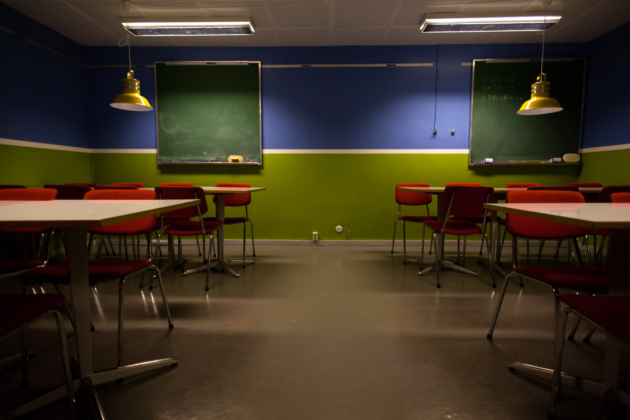 a classroom with desks and chairs, lights and chalkboard