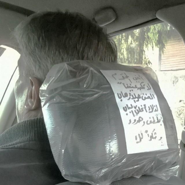 a man driving in a car with a bag