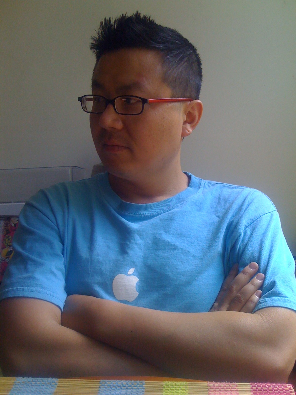 an apple t - shirt that has the logo on it is sitting next to a woman wearing glasses