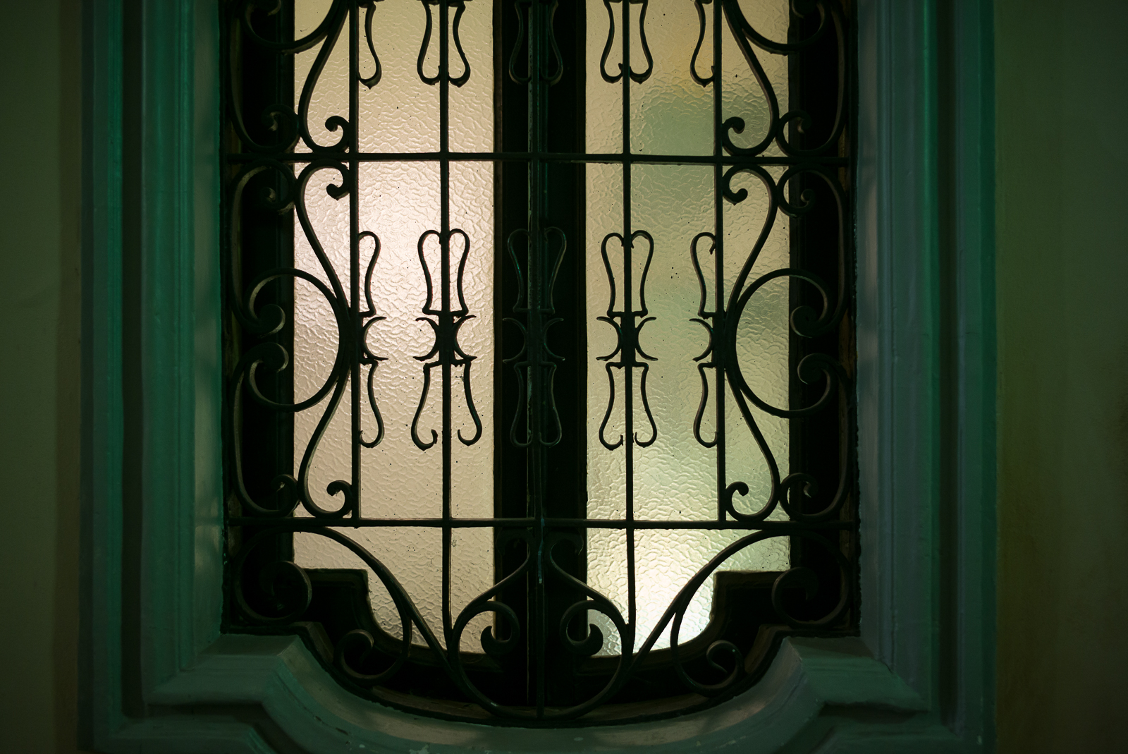 window with metalwork and stained glass on a green door