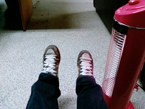 person wearing red sneakers sitting in front of a red fan