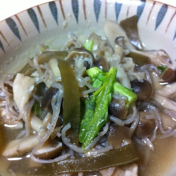 a bowl with noodles, green vegetables and onions