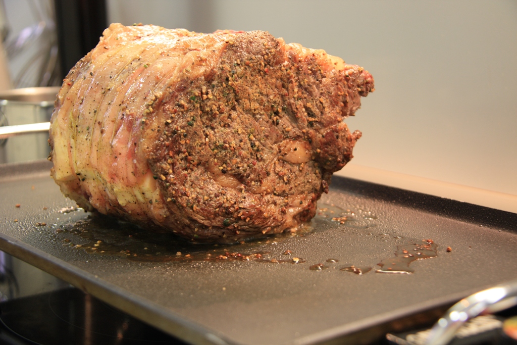 meat being prepared on a cooking sheet, with seasoning