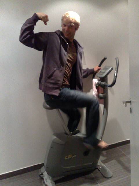 an older man in a jacket and tie riding on an exercise bike